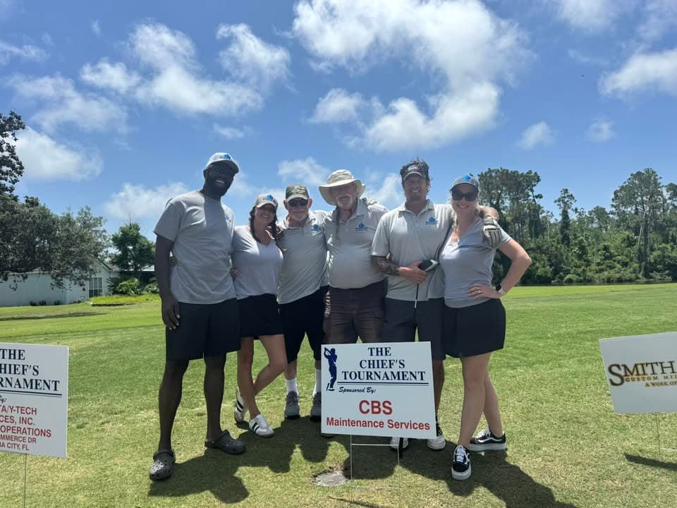 The CBS Maintenance Services team at The Chief's Tournament, standing behind a sponsor board bearing the company name